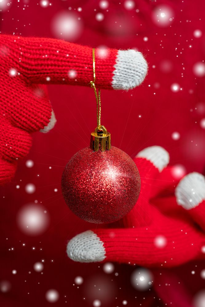 Hand wearing red gloves holding Christmas bauble ball