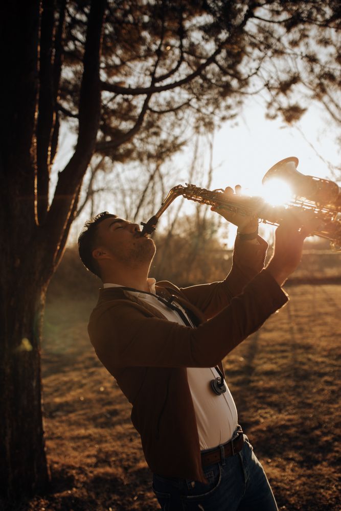 young musician playing the saxophone at sunset