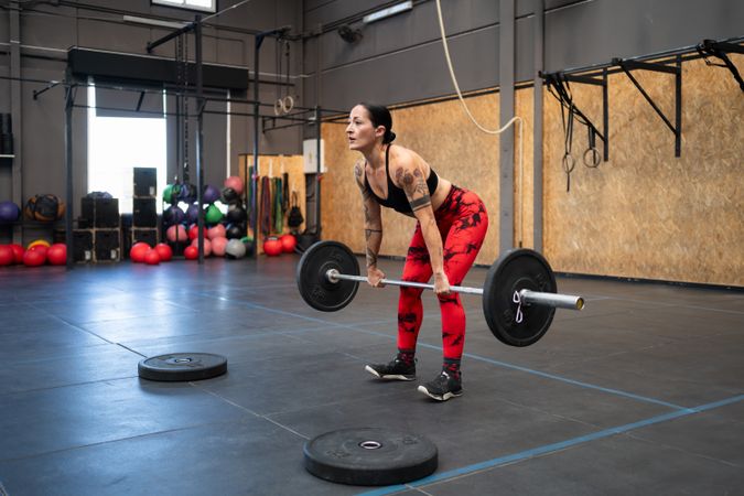 Fit woman dead-lifting in a cross training center