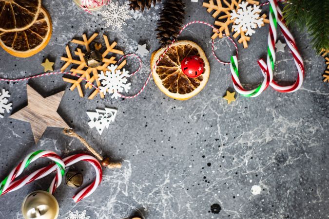 Christmas ornaments, candy canes and fir scattered on marble table