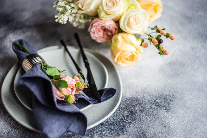 Pink flowers on grey plate with navy napkin with yellow bouquet