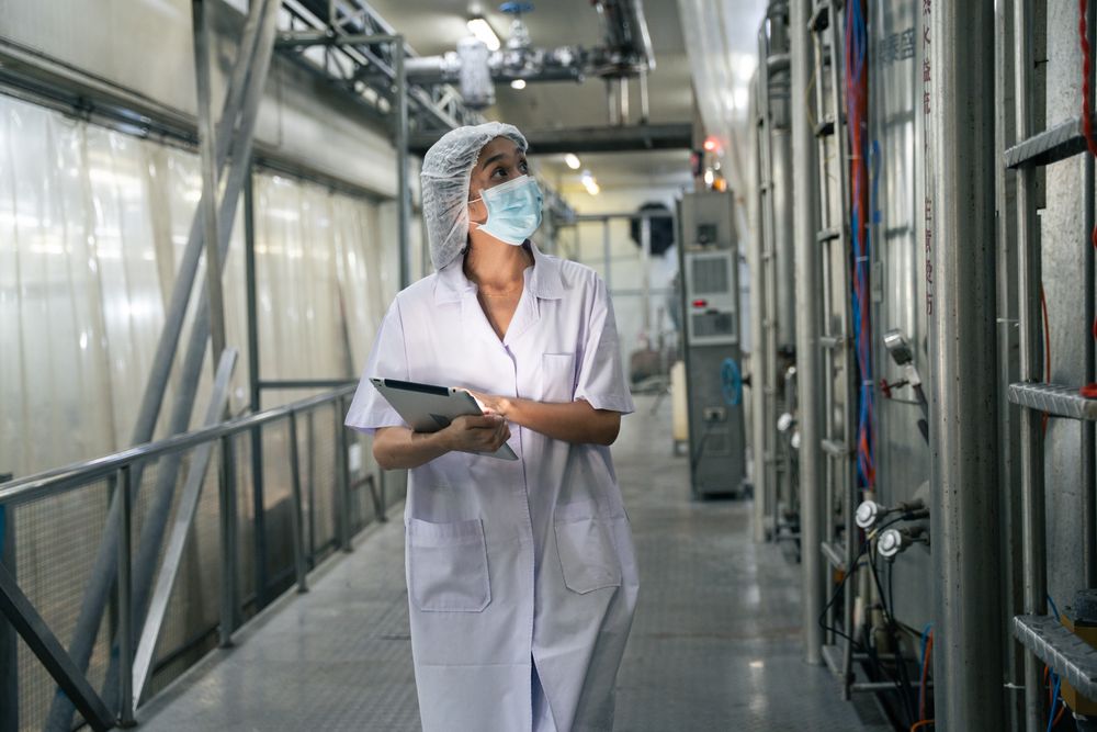 A food factory researcher inspecting canned food conveyor belt machine.