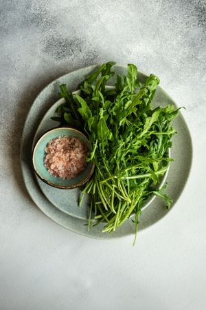 Looking down at plate with bunch of arugula and pink salt