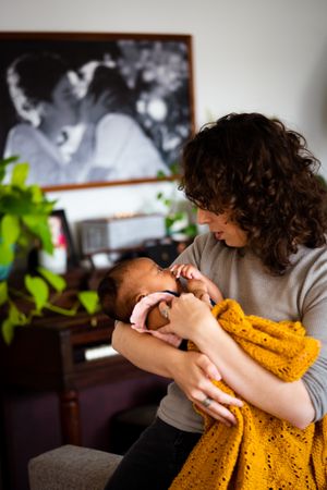 Mother tenderly holding baby girl at home