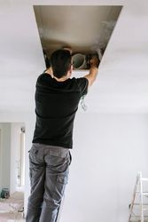 Man preparing extractor hood installation on kitchen ceiling