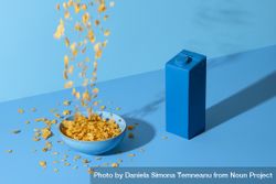 Pouring cornflakes cereal in a bowl on a blue table 4Nn1D4