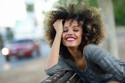 Smiling female in casual dress sitting on park bench