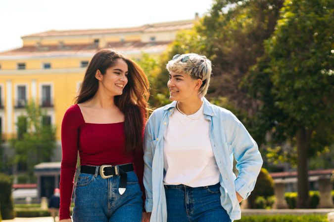 two young women walking and smiling in a park