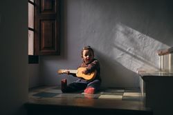 Girl playing ukulele on floor at home