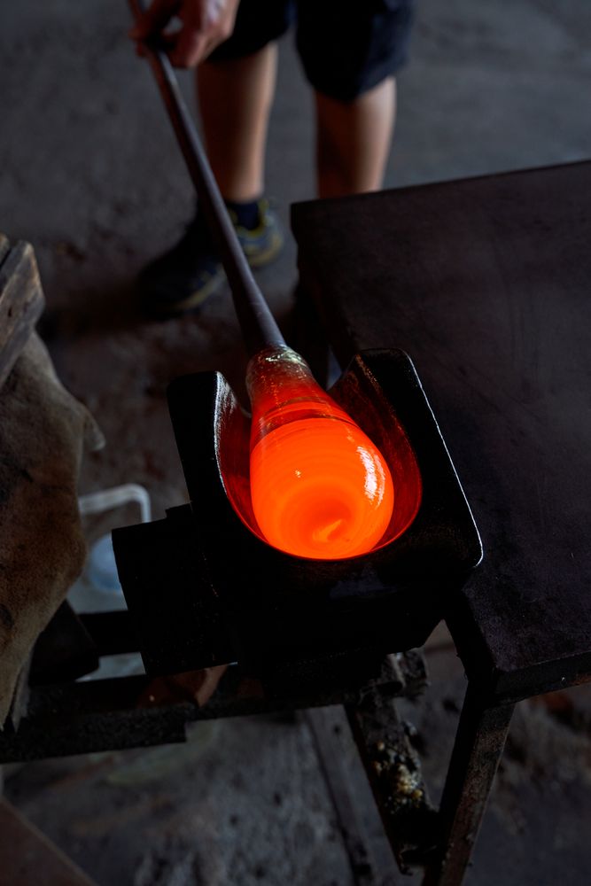 Crop man with molten glass on blowpipe