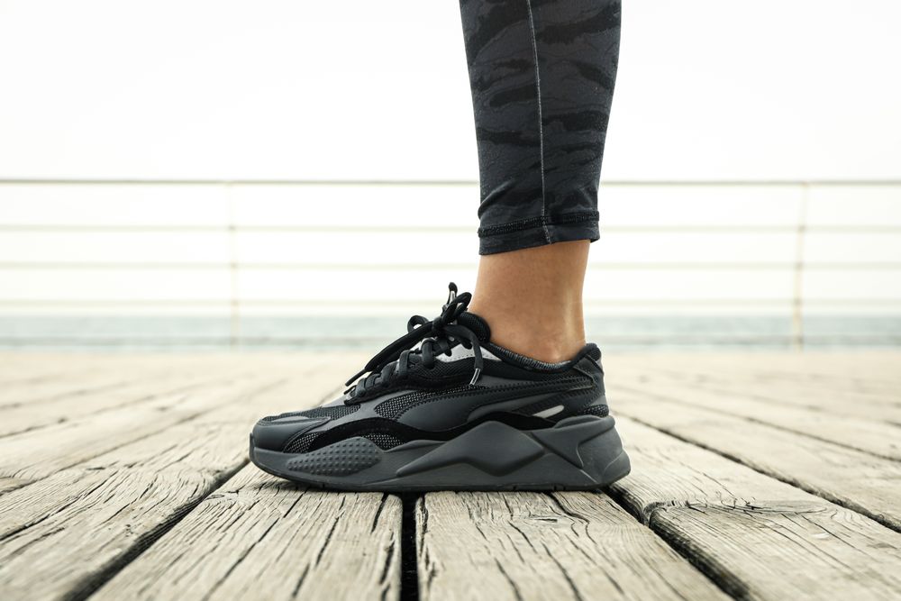 Young woman in sneakers doing sports near sea, close up