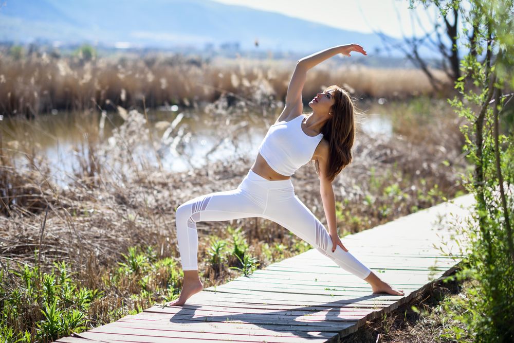 Young woman doing yoga with beautiful mountains in the background