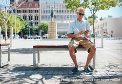 Male tourist sitting on bench outside in the city 5a3xAb