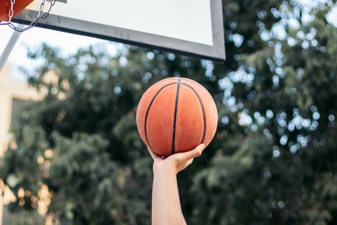 Close-Up of Hand Holding Basketball Near the Hoop