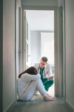 Psychiatrist talking to patient sitting on the floor in a mental health center