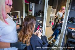 Woman showing hairdresser image on phone of what style she wants 5rVYM5