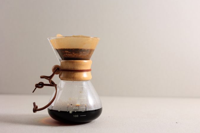 Glass Coffeemaker with Tasty Drip Coffee on Cream Table