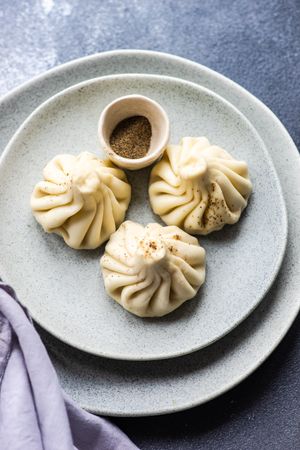 Top view of grey plate with three Georgian khinkali dumplings