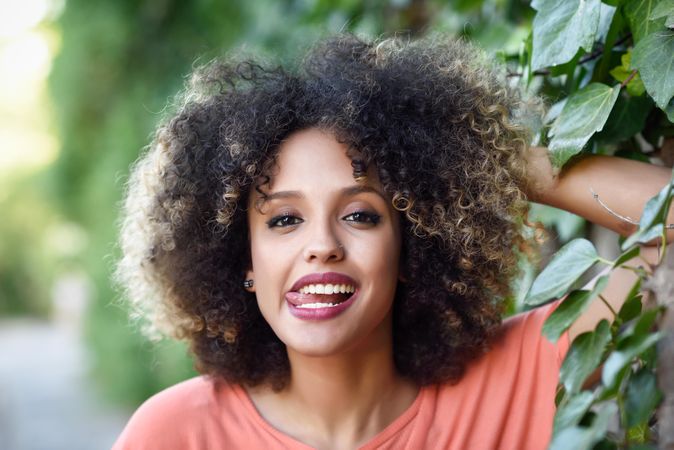 Portrait of playful Black woman with afro hairstyle in front of wall with vines