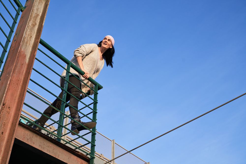 Cheerful woman in pink scarf leaning on metal fence