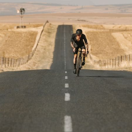 Sportsman cycling uphill on the empty road