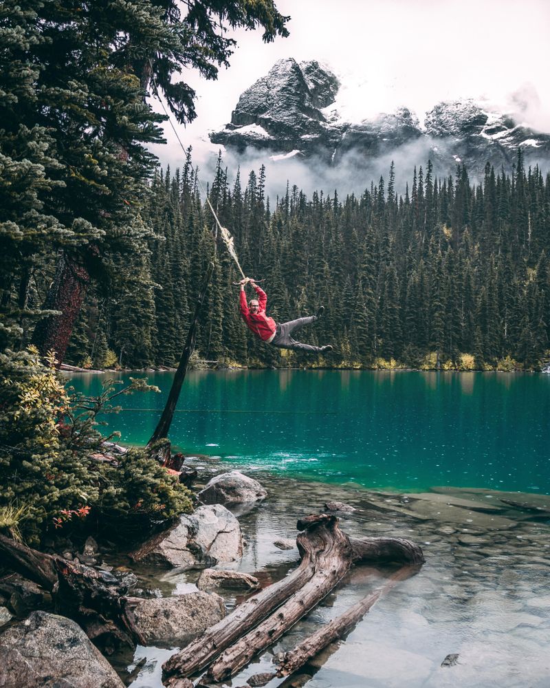 Man swinging rope and jumping in lake