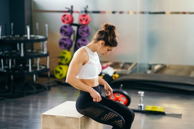 Muscular woman sitting on box in gym