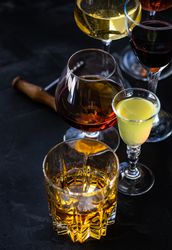 Glasses of different spirits on dark background