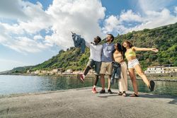 Energetic group of diverse friends celebrating with open arms on a pier during summer vacation.