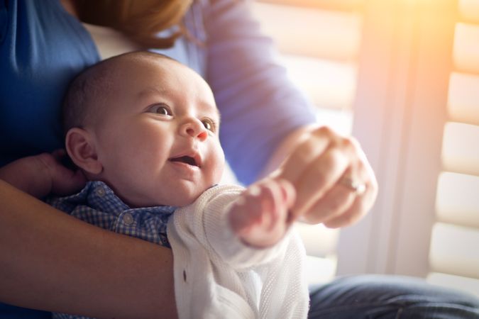 Happy Couple Enjoying Their Newborn Son In The Light of The Window.