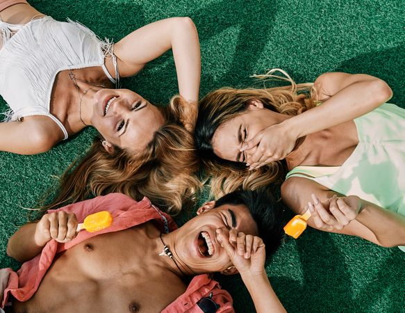 a group of young people having a good time and eating ice-cream lying on grass