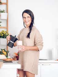 Smiling female pouring coffee from moka pot in kitchen