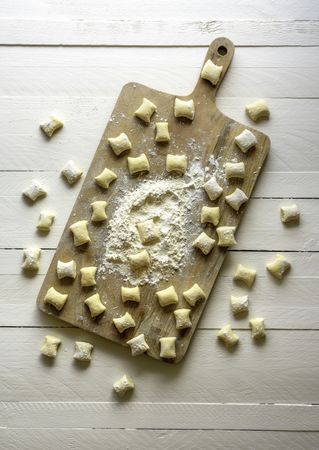 Uncooked gnocchi on wooden board