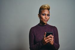 Black woman thinking about a text on a cell phone