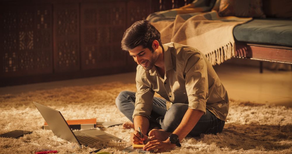 Smiling Indian Man Studying at Home: Engaged in Learning, Researching, and Project Management.