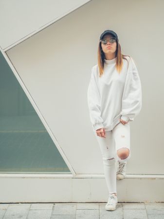 Young woman with glasses standing against wall
