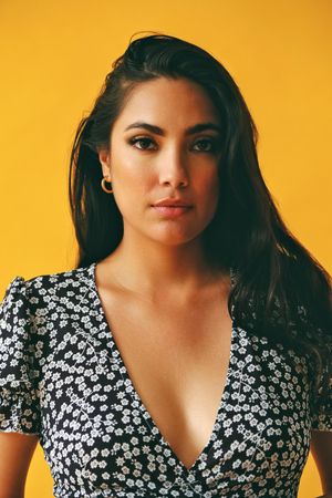 Hispanic woman wearing dress in yellow room, vertical