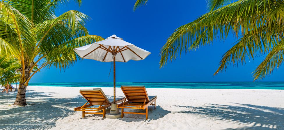 Relaxing lounge chairs and parasol on a tropical beach, wide shot