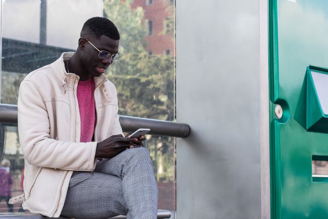 Black male entrepreneur browsing smartphone on train platform