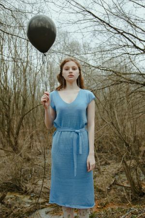 Woman in blue dress holding a dark balloon
