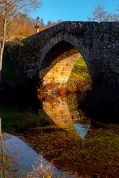 Old bridge over calm river in autumn countryside