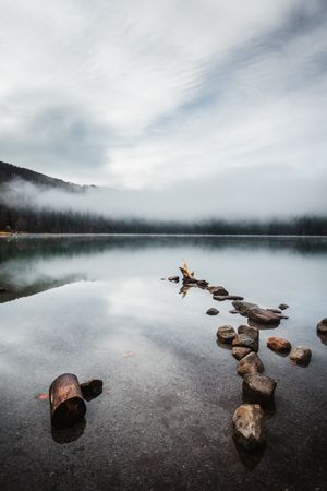 Brown rocks on lake under cloudy sky