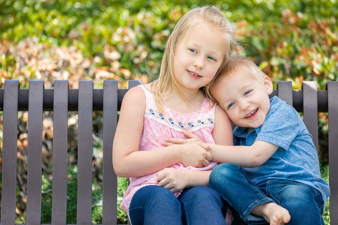 Young Sister and Brother Having Fun On The Bench At The Park