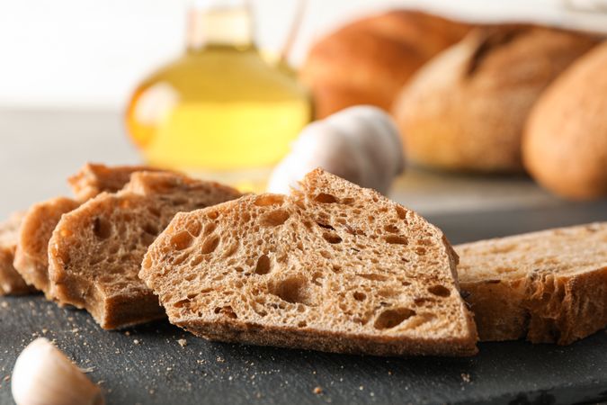 Composition with bakery products, garlic and olive oil on grey background, closeup and space for text
