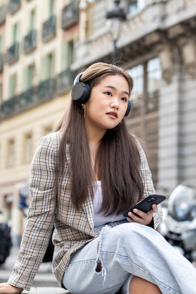 Young Asian woman listening to music with smartphone in the city