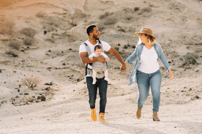 Diverse parents dancing while walking with baby