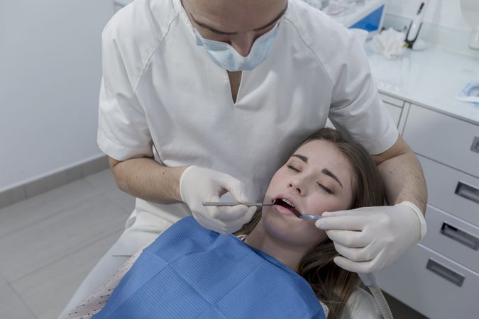 A portrait of a dentist working on the mouth of a female patient