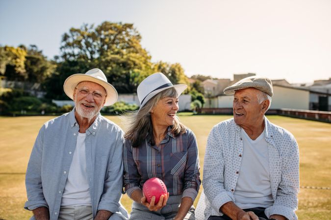 Woman sitting with her male friends with a boules in hand