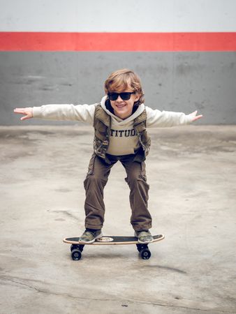 Stylish child riding skateboard on street