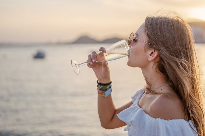 Young woman enjoying wine near sea